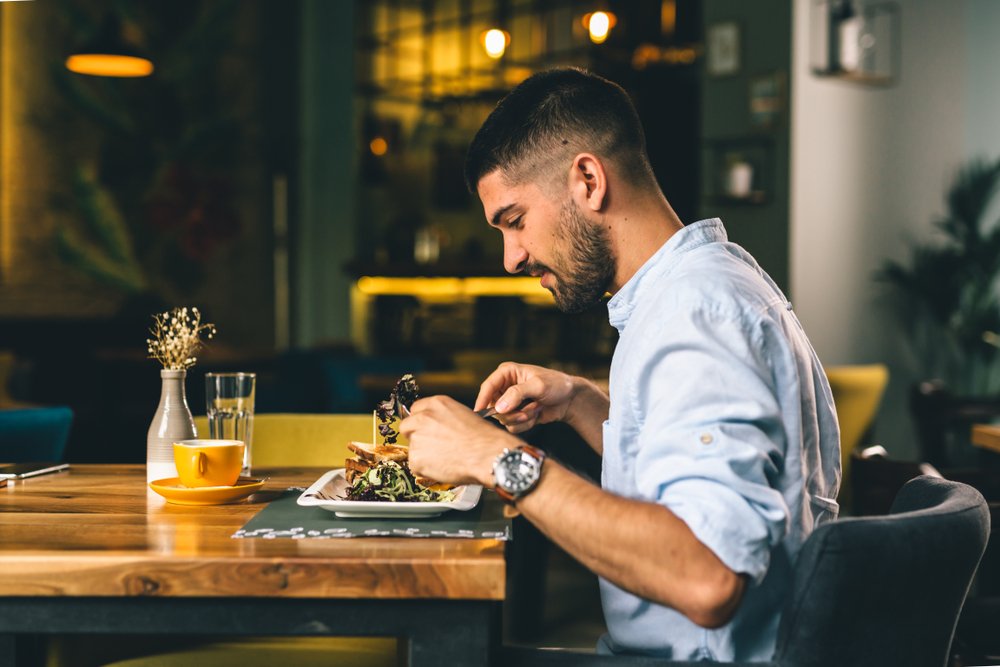 man having breakfast or dinner in cafe