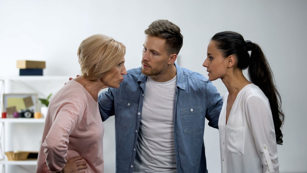 Man trying to calm wife and mother arguing, in-law conflict