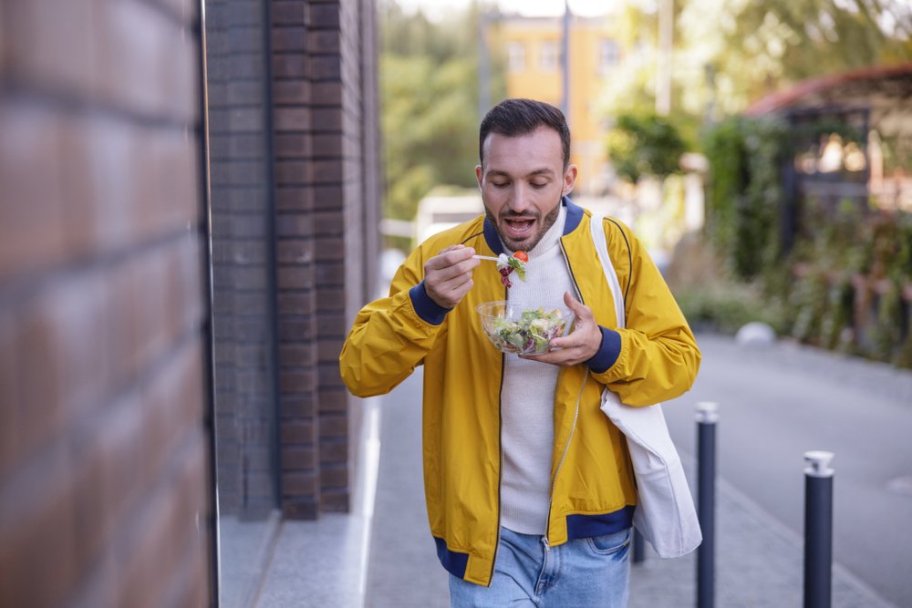 eating his salad while being on the street