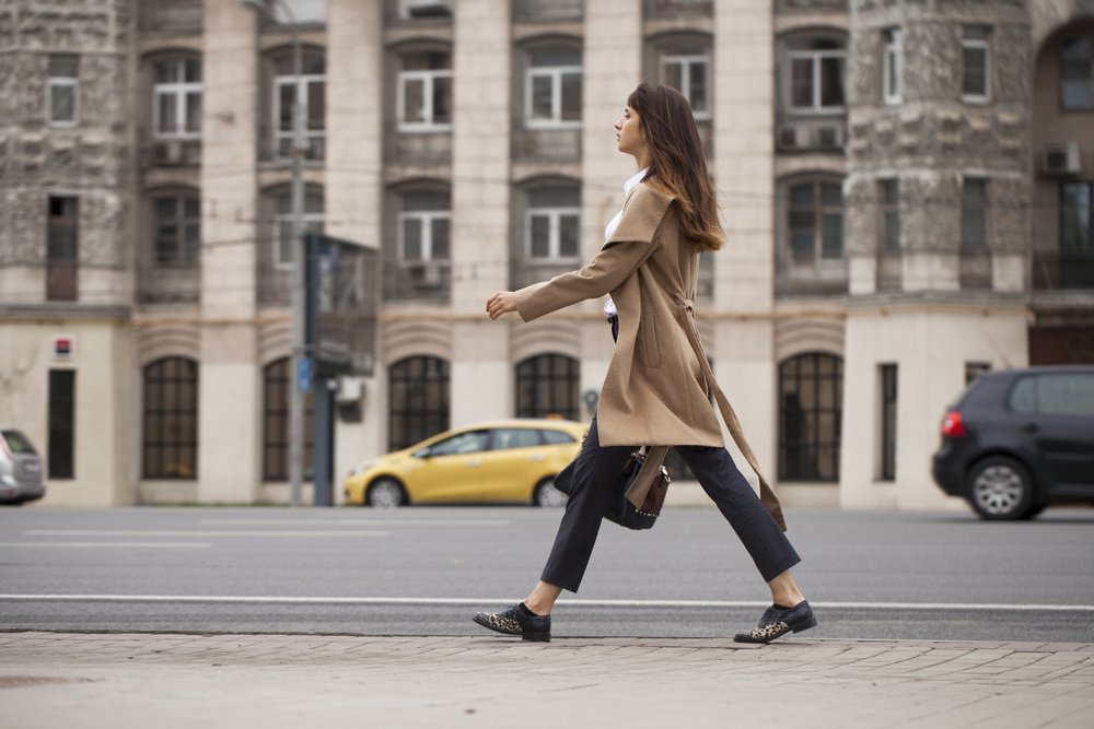 woman in beige coat with a bag walking
